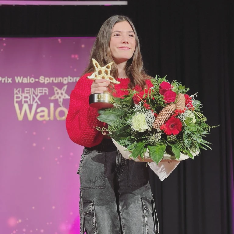 Liana Sounds holding her Kleiner Prix Walo award and flowers on stage